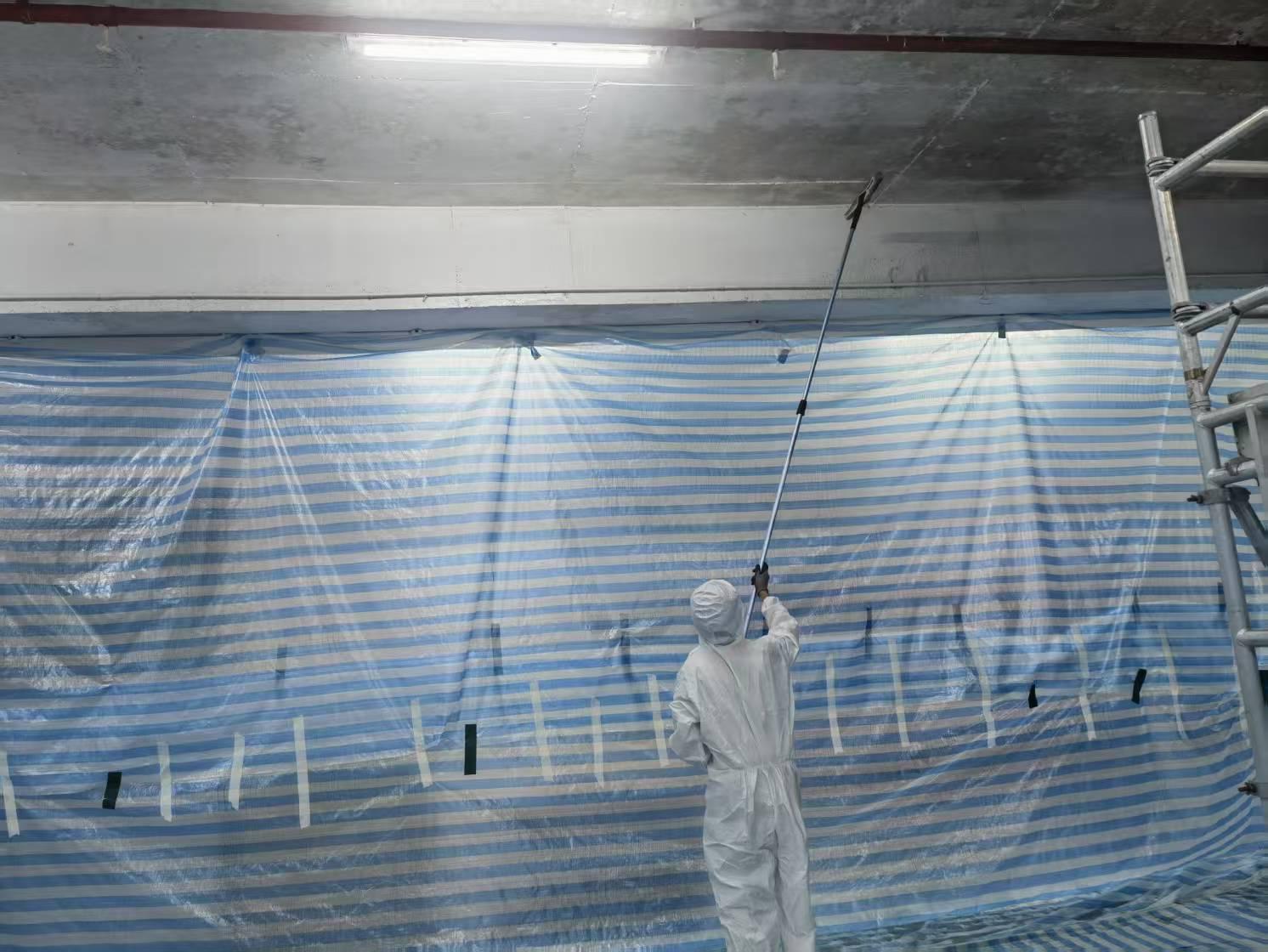 Worker applying RD-Aquasorb to the ceiling using an airless sprayer